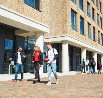 Three students walking through Bay Campus